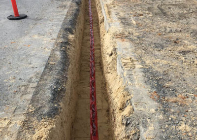 Backfilling installed Super main pipe with PM64 sand and identification warning tape indicating fire main below at a Railyard in Regency park